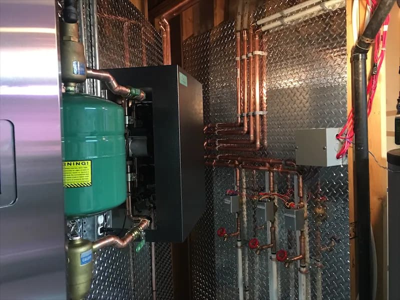 Green expansion tank mounted beside a boiler with copper supply and return lines