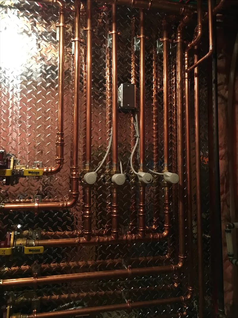 Copper heating risers and shut-off valves running up a mechanical room wall