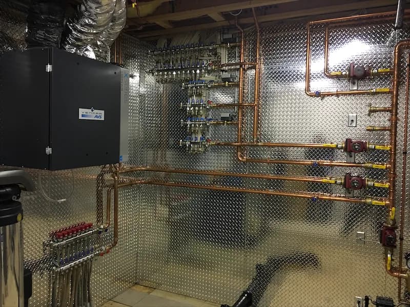 In-floor heating manifold and copper distribution piping in an unfinished mechanical room
